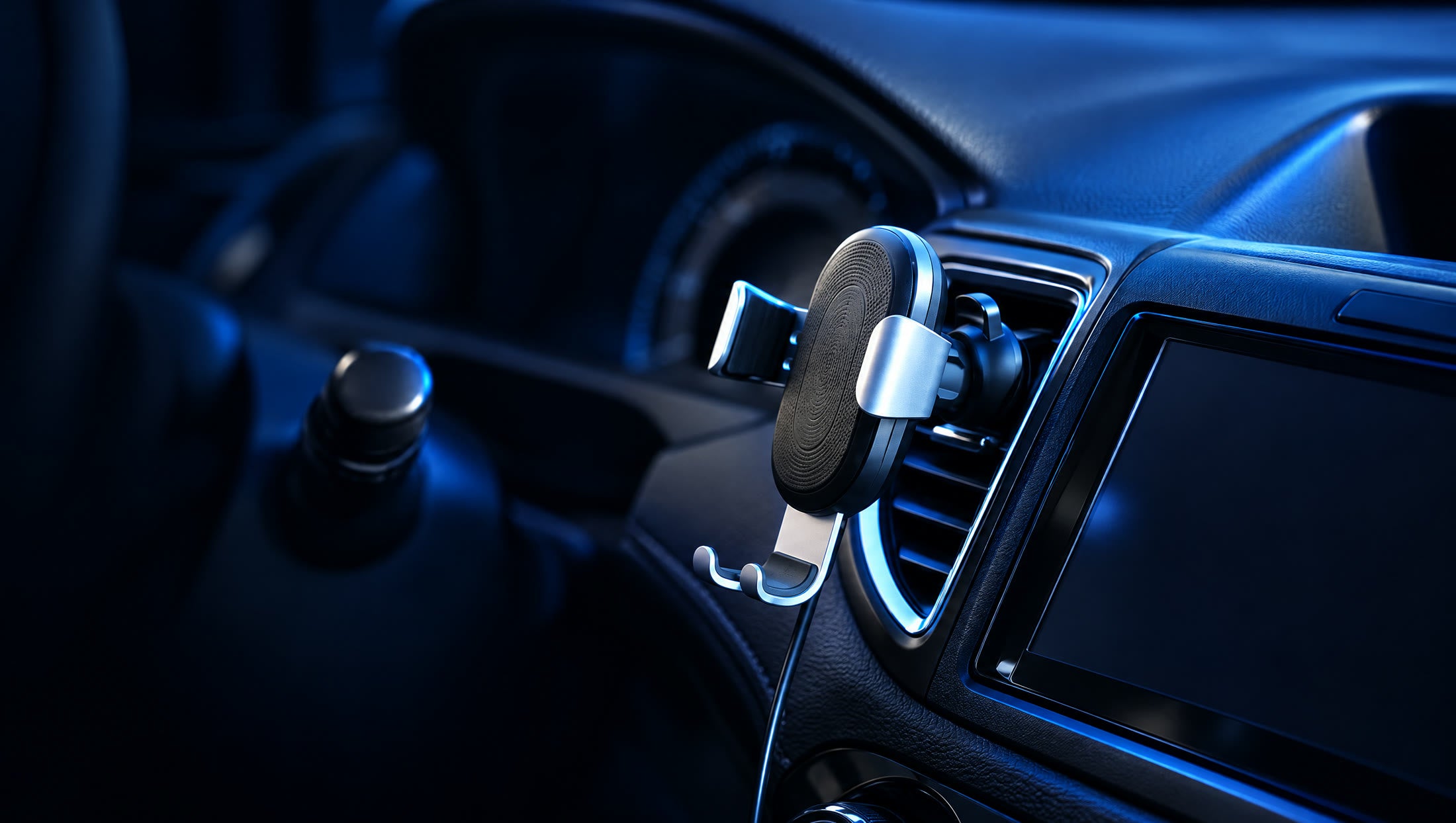 A wireless charging phone mount clipped to a car air vent, lit in dark blue